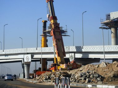 Cairo, Egypt, February 16 2023: Construction site of new Cairo monorail overhead transportation system that is still under construction with a heavy mobile crane fixing and fitting objects