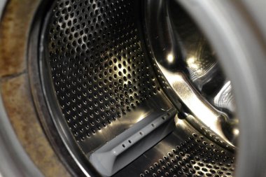 Stainless steel washing machine drum with an open door of the washer, washing machine maintenance, fixing machine and replacement concept, selective focus