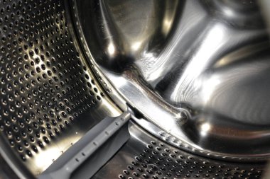 Stainless steel washing machine drum with an open door of the washer, washing machine maintenance, fixing machine and replacement concept, selective focus