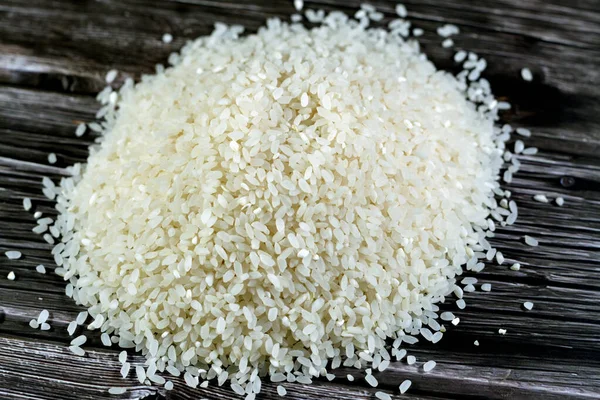 A pile of raw short grain white rice, White rice is milled rice that has had its husk, bran, and germ removed, seeds are with a bright, white, shiny appearance, selective focus of uncooked rice