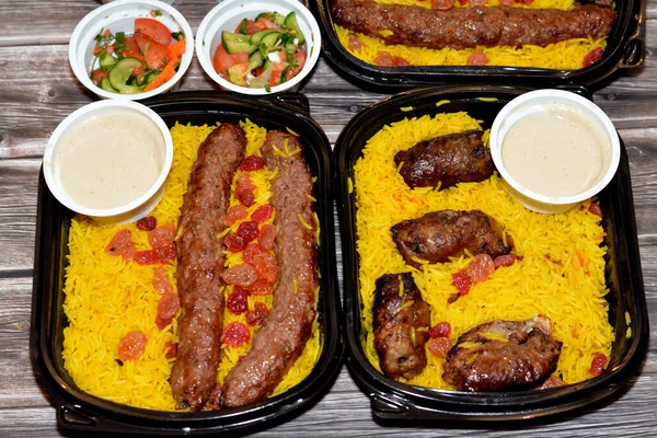 Arabic cuisine traditional food beef  Kofta, kebab and tarb kofta shish which is minced meat with Basmati rice and raisins, oriental grilled barbecued meat food with long yellow rice, selective focus