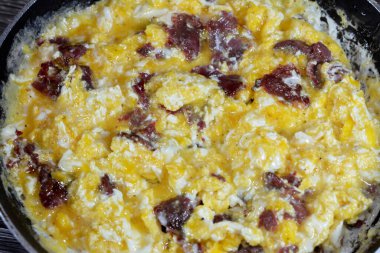 Scrambled eggs with pastrami, a dish made from eggs stirred, whipped or beaten together while being gently heated, with salt, butter, oil and black pepper with slices and pieces of beef pastrami