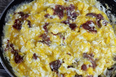 Scrambled eggs with pastrami, a dish made from eggs stirred, whipped or beaten together while being gently heated, with salt, butter, oil and black pepper with slices and pieces of beef pastrami