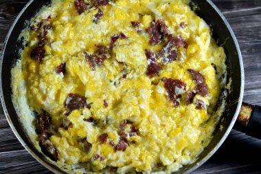 Scrambled eggs with pastrami, a dish made from eggs stirred, whipped or beaten together while being gently heated, with salt, butter, oil and black pepper with slices and pieces of beef pastrami