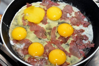 Eggs to be scrambled with pastrami, a dish made from eggs stirred, whipped or beaten together while being gently heated, with salt, butter, oil and black pepper with slices and pieces of beef pastrami