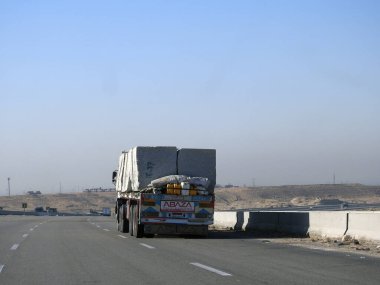 Giza, Egypt, January 26 2023: A big truck loaded with large blocks of stone, limestone, rocks taken from quarries in mountains being transferred on a highway with a large lorry, selective focus