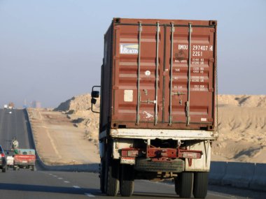 Giza, Egypt, January 26 2023: flatbed truck big vehicle with a steel shipment container on it on a highway in Egypt, shipment and delivery service concept, lorry transfer container, selective focus