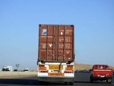 Giza, Egypt, January 26 2023: flatbed truck big vehicle with a steel shipment container on it on a highway in Egypt, shipment and delivery service concept, lorry transfer container, selective focus