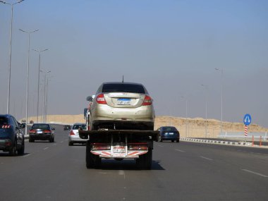 Kahire, Mısır, 8 Mart 2023: Bir çekici kurtarma taşıyıcısı hidrolik kamyon bozuk bir arabayı yolda hareket ettiriyor, bakım için sokaktan bir arabayı kurtarmanın seçici odak noktası