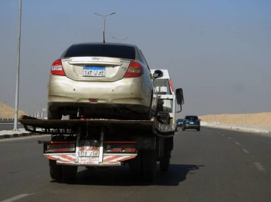 Kahire, Mısır, 8 Mart 2023: Bir çekici kurtarma taşıyıcısı hidrolik kamyon bozuk bir arabayı yolda hareket ettiriyor, bakım için sokaktan bir arabayı kurtarmanın seçici odak noktası