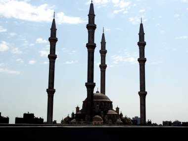 Gündüz vakti beton ve çelikten yapılmış çok sayıda minaresi ve kubbesi olan büyük bir cami. Gökyüzü arka planına karşı büyük bir İslam camisinin seçici odak noktası.