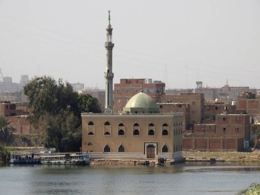 Giza, Mısır, 9 Mart 2023: Nil nehri kıyısında yeşil kubbeli ve uzun minareli güzel küçük bir cami, Nil kıyısındaki bir cami, seçici bir odak noktası