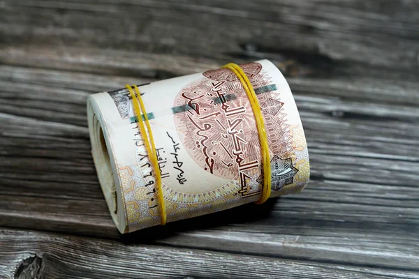 Egypt money bundle roll of pounds, 1 EGP LE one Egyptian pound cash money bills rolled up with rubber bands with a image of Mosque and mausoleum of Qaitbay and Abu Simbel temples isolated on wood