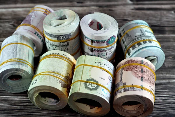 Background of bundles and rolls of Egyptian money currency cash banknotes rolled up with rubber bands in different bill values of 1 LE, 5, 10, 20 EGP and fifty piasters, one, five, ten, twenty pounds