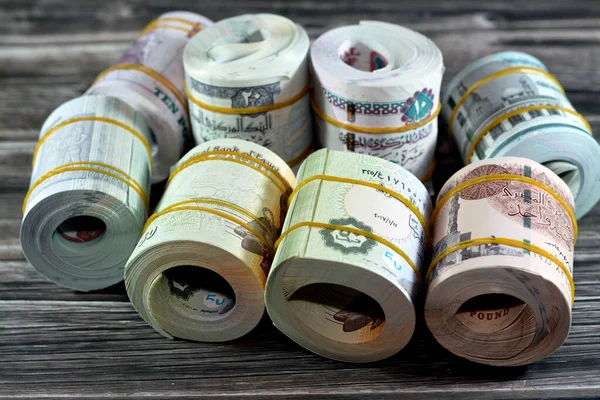 Background of bundles and rolls of Egyptian money currency cash banknotes rolled up with rubber bands in different bill values of 1 LE, 5, 10, 20 EGP and fifty piasters, one, five, ten, twenty pounds
