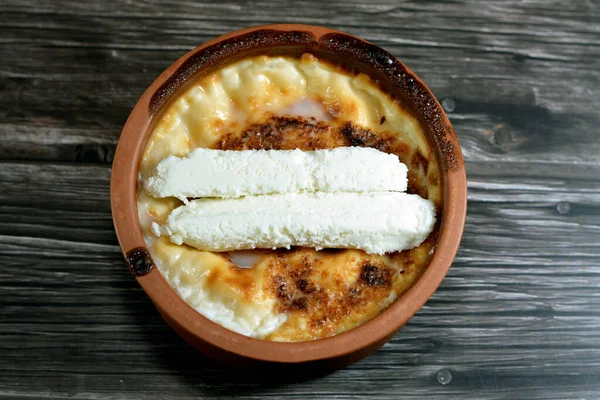 stock image Rice pudding pottery casserole topped with milk cream, rice, corn flour, sugar, water or milk and other ingredients such as cinnamon, vanilla, called Stla, Sholezard, moghli baked