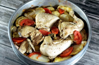 Fırında pişirilmeye hazır fırında tavuk butları, bacaklar ve göğüsler patates dilimleri, soğan ve domates, domates sosu, ghee ve baharatla birlikte, Mısır Arap tavuk mutfağı.