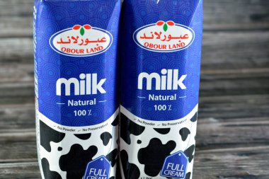 Kahire, Mısır, 16 Mart 2023: Obour Land tam kremalı inek sütü şişesi. 1 litre litrelik koruyucu madde ve toz yok, seçici odak noktası ahşap arka planda.