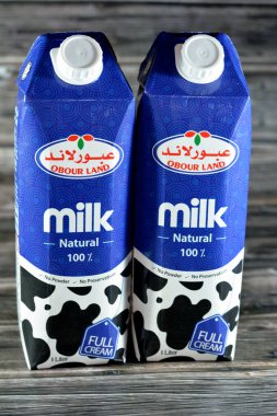 Kahire, Mısır, 16 Mart 2023: Obour Land tam kremalı inek sütü şişesi. 1 litre litrelik koruyucu madde ve toz yok, seçici odak noktası ahşap arka planda.