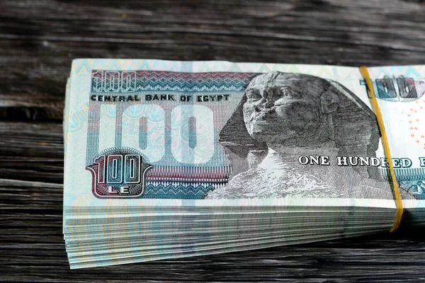 Stack of Egyptian currency of 100 EGP LE one hundred Egyptian pound bills, spending, giving and using money concept, paying and buying using banknotes with Sultan Hassan mosque and the Sphinx