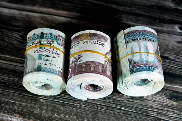 Rolls of Egypt money banknote bills of 100 and 50 EGP LE one hundred Egyptian and fifty Pounds isolated on wood features Sultan Hassan and Abu Hurayba Mosques, Sphinx, Edfu temple and winged scarab