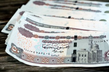 Mısır para yığını ahşap arka planda izole edilmiş 50 EGP LE 50 Mısır sterlini nakit para banknotları Ebu Hurayba Camii 'nin resmi, Edfu tapınağı ve kanatlı böcek, seçici odaklı
