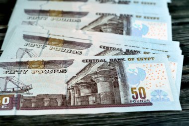 Mısır para yığını ahşap arka planda izole edilmiş 50 EGP LE 50 Mısır sterlini nakit para banknotları Ebu Hurayba Camii 'nin resmi, Edfu tapınağı ve kanatlı böcek, seçici odaklı