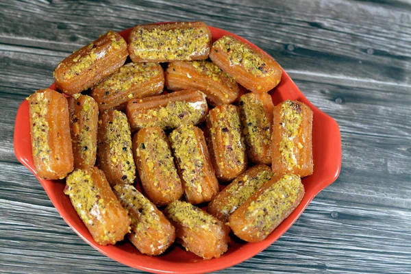 Tulumba, Bamiyeh or Balah El Sham stuffued with whipped cream and covered with pistachios and nuts, deep fried batter dessert soaked in syrup, similar to jalebis and churros, balah ash-sham in Arabic