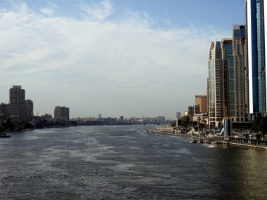 Kahire, Mısır, 16 Nisan 2023: Nil nehri, modern binalar ve Nil kıyısı boyunca köprüler bulunan Mısır nehri ve Mısır nehri, Kahire şehrinin gündüz vakti nehir kıyısında yürüyor.