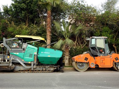 Kahire, Mısır, 7 Nisan 2023: Asfalt kaldırım kamyonları ve sıkıştırıcılar, bir kaldırım taşı (Road Paver finisher, asfalt kaldırım makinesi) asfalt beton döşemek için kullanılan bir yapı malzemesidir.