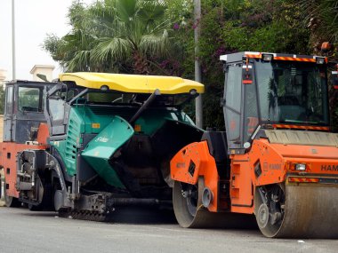 Kahire, Mısır, 8 Nisan 2023: Asfalt kaldırım kamyonları ve sıkıştırıcılar, bir kaldırım taşı (Road Paver finisher, asfalt kaldırım makinesi) asfalt beton döşemek için kullanılan bir yapı malzemesidir.