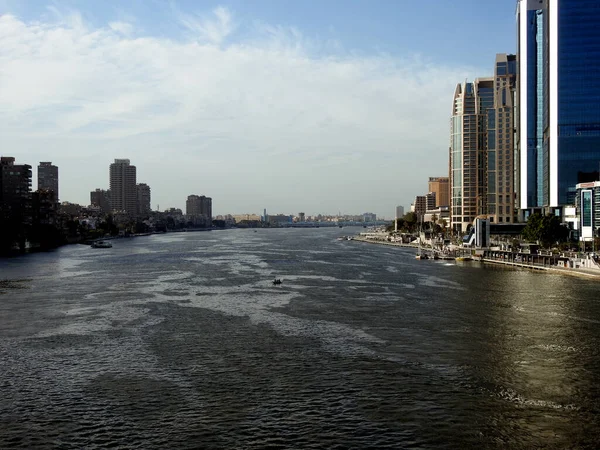 stock image Cairo, Egypt, April 16 2023: The river Nile of Egypt  with modern buildings and bridges along the Nile bank and the Egyptian walk on the river coast at the daylight of Cairo city, selective focus