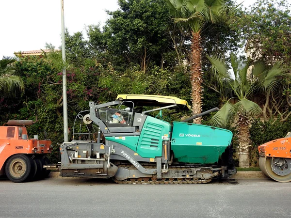 stock image Cairo, Egypt, April 7 2023: Asphalt paver trucks and compactors, A paver (road paver finisher, asphalt finisher, road paving machine) is a piece of construction equipment used to lay asphalt concrete