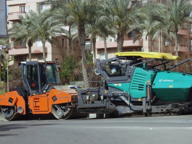 Kahire, Mısır, 18 Nisan 2023: Asfalt kaldırım kamyonları ve sıkıştırıcılar, bir kaldırım taşı (Road Paver finisher, asfalt kaldırım makinesi) asfalt beton döşemek için kullanılan bir yapı malzemesidir.