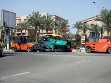 Kahire, Mısır, 18 Nisan 2023: Asfalt kaldırım kamyonları ve sıkıştırıcılar, bir kaldırım taşı (Road Paver finisher, asfalt kaldırım makinesi) asfalt beton döşemek için kullanılan bir yapı malzemesidir.