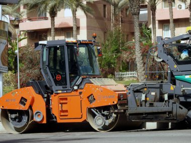 Kahire, Mısır, 18 Nisan 2023: Asfalt sıkıştırıcı hammer kamyonu, bir kaldırım taşı (Road Paver finisher, asfalt kaldırım makinesi) asfalt beton döşemek için kullanılan bir yapı malzemesidir.