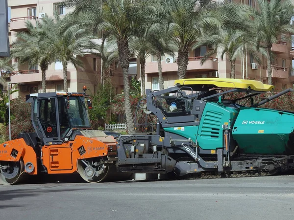 Kahire, Mısır, 18 Nisan 2023: Asfalt kaldırım kamyonları ve sıkıştırıcılar, bir kaldırım taşı (Road Paver finisher, asfalt kaldırım makinesi) asfalt beton döşemek için kullanılan bir yapı malzemesidir.