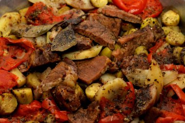 Bir tepsi patates dilimi, soğan, domates, renkli biber, et parçaları, baharatlar, sarımsak ve kırmızı biber, seçici patates, sığır eti ve sebze ile fırında