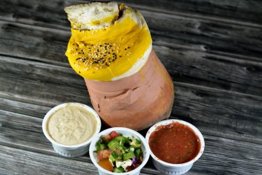 İçinde hamur, susam ve kuzu bacağı ile kaplı bir çömlek kavanozu var. İçinde Basmati pilavı, karışık sebzeler ve doldurulmuş üzüm yaprakları var. Mahshi Mahshy pilavı yavaşça fırında kızartılıyor.