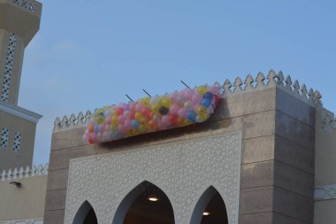 Kahire 'deki bir caminin önünde, minarenin yanındaki caminin çatısında bayram namazından sonra çocuklar için atılacak onlarca balonla şenlik ve kutlamaların arka planı.
