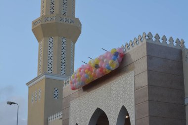 Kahire 'deki bir caminin önünde, minarenin yanındaki caminin çatısında bayram namazından sonra çocuklar için atılacak onlarca balonla şenlik ve kutlamaların arka planı.
