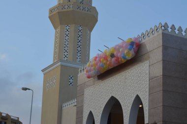 Kahire 'deki bir caminin önünde, minarenin yanındaki caminin çatısında bayram namazından sonra çocuklar için atılacak onlarca balonla şenlik ve kutlamaların arka planı.