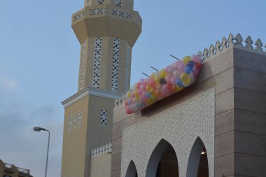 Kahire 'deki bir caminin önünde, minarenin yanındaki caminin çatısında bayram namazından sonra çocuklar için atılacak onlarca balonla şenlik ve kutlamaların arka planı.