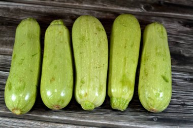 Taze yeşil kabak yığını veya ahşap zemin üzerinde izole kabak sebzeler, taze çiğ organik kabak sebzeleri seçici odak sağlıklı gıda tarım vegan ve kilo kaybı konsepti