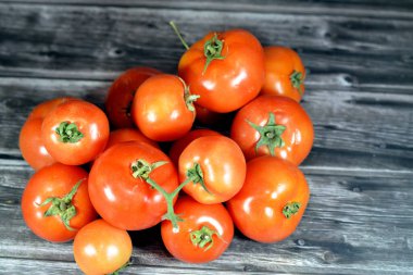 Tahta arka planda izole edilmiş taze kırmızı domates yığını, taze çiğ organik domates seçici odak, sağlıklı gıda tarım vegan ve kilo kaybı konsepti