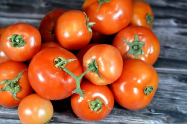 Tahta arka planda izole edilmiş taze kırmızı domates yığını, taze çiğ organik domates seçici odak, sağlıklı gıda tarım vegan ve kilo kaybı konsepti