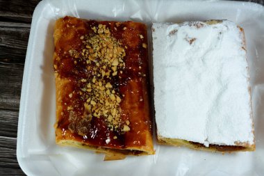 Elmalı turta, kremalı elma, tarçın ve şekerli bal şurubuyla doldurulmuş ve üzerinde şam fıstığı, fındık ve krema şekeri, lezzetli, tatlandırılmış elmalı turta servis edilmeye hazır, seçici bir odaklanma.