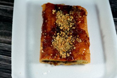 Elmalı turta, kremalı elma, tarçın ve şekerli bal şurubuyla doldurulmuş ve üzeri şam fıstığı ve fındıklı, lezzetli tatlandırılmış elmalı turta servis edilmeye hazır, seçici odaklanma.