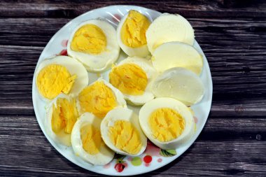 Haşlanmış yumurta dilimleri önceden kaynamış suda pişirilir, parçalara ayrılır ve küçük bir tabakta servis edilir. Ahşap bir arka planda izole edilir. Kahvaltıda iyi bir atıştırmalık ve gündüz vakti.
