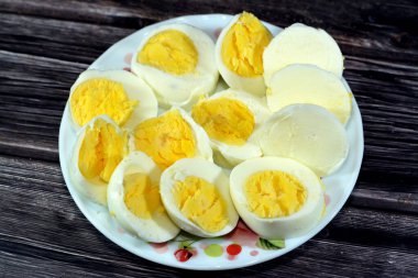 Haşlanmış yumurta dilimleri önceden kaynamış suda pişirilir, parçalara ayrılır ve küçük bir tabakta servis edilir. Ahşap bir arka planda izole edilir. Kahvaltıda iyi bir atıştırmalık ve gündüz vakti.